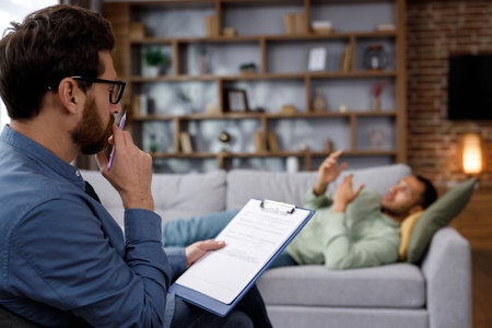 A visit to the psychologist of an African American man. A handsome man is lying on the couch and talking to a psychotherapist. Depression, apathy, stress, burnout at work. Help of a psychologist.の写真素材