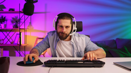 Gamer bearded guy, in a gaming headset, wins a video game. Cybersportsman in a neon room. Lifestyle gamer, online games. Victory in the E-Sport tournamentの写真素材