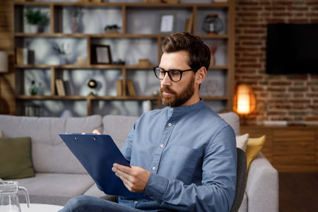An adult handsome man sits at home in a stylish office. Psychologist, coach or businessman looking at the camera and smiling. Beautiful teeth and smile.の写真素材