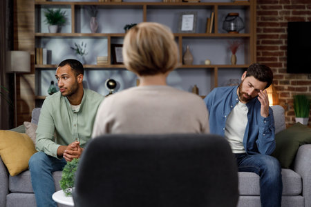 Family quarrel at the reception at the psychologist. LGBT couple at a psychotherapists appointment. Psychologist for gays. Support for the LGBT community in visiting a psychologist.の写真素材