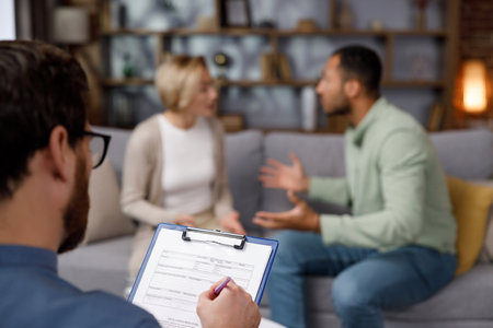 Multiracial quarrel between husband and wife at a session with a psychotherapist. A visit to a family psychologist for a married couple. A doctor consults an unhappy married couple. Help psychologist.の写真素材