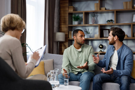 Family quarrel at the reception at the psychologist. LGBT couple at a psychotherapists appointment. Psychologist for gays. Support for the LGBT community in visiting a psychologist.の写真素材