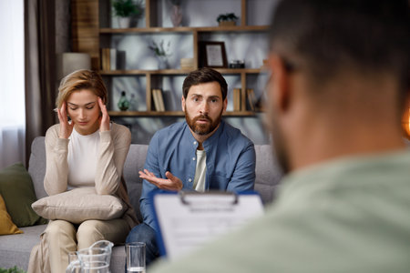 A quarrel between a husband and wife at a psychotherapists appointment. A visit to a family psychologist for a married couple. An African-American doctor consults an unhappy couple.の写真素材