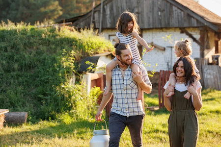 Happy young family enjoy spending time together on weekend at the countryside. Mother, father and two kids walking near their wooden country house. Moving from urban areas to rural areas concept.の写真素材