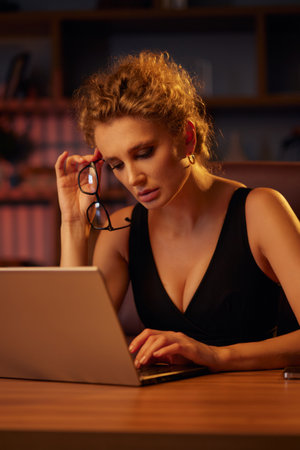 Purposeful young business woman, professional entrepreneur, works behind a laptop. Businesswoman, in a beautiful office in cinematic light. Finance, startups, stock trading, online workの写真素材