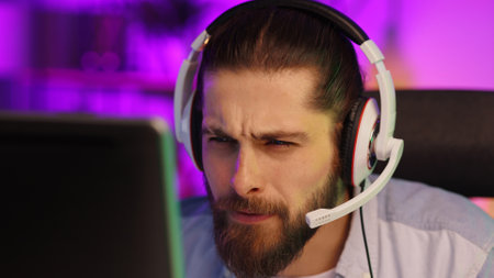 Close-up portrait of an esportsman. A professional gamer plays a computer video game, communicates in a headset with a team at the E-Sport championship. cyber gaming arena.の写真素材