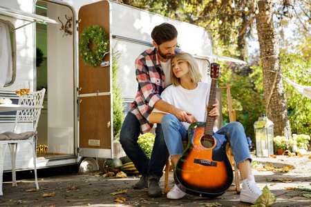Young couple in love in nature near a tourist trailer are cutely hugging. Rest outside the city in the summer, mutual love, happy memories.の写真素材