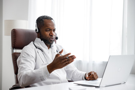 African American male doctor welcomes online patient consultation in laptop. An office providing telemedicine services. online medicine and telemedicine concept.の写真素材