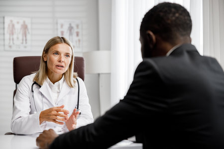 A woman doctor receives an African American male patient in her office. Doctors consultation.の写真素材