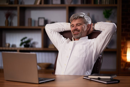 A successful man rests, reclases while sitting at the workplace. Businessman, manager in home comfortable office relaxed after successful work.の写真素材