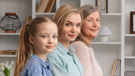Cute little girl posing indoors with young mother and senior grandmother, side profile view, closeup portrait. Lifespan, next generation, offspring and heredity. For Mothers Day.の写真素材