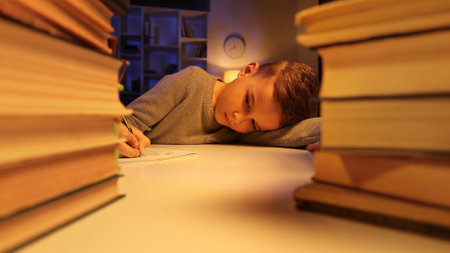 A small schoolboy lies tired from a lot of homework, completes the assignment, falls asleep tired. The concept of childrens overload, fatigue from school.の写真素材