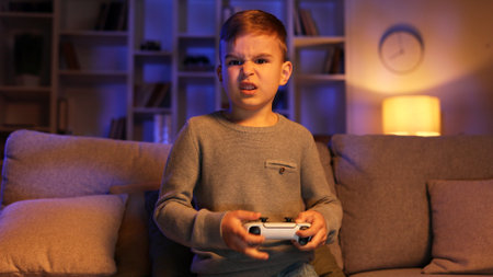 Portrait of a happy child playing a video game very hard with a joystick, looking intently at the camera at home. The concept of games and childhood.の写真素材