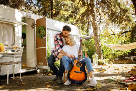 Young couple in love in nature near a tourist trailer are cutely hugging. Rest outside the city in the summer, mutual love, happy memories.の写真素材