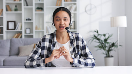 A young girl works in a call center, talks to customers. African-American business woman working from home on a laptop, making a work video call. View from the webcam.の写真素材