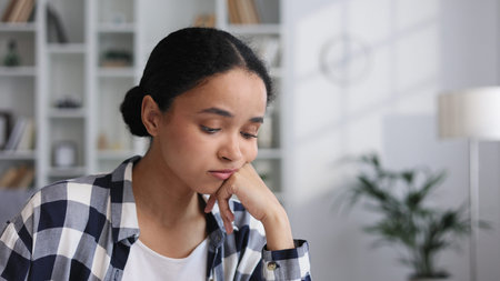 Attractive African American girl sitting in living room, resting