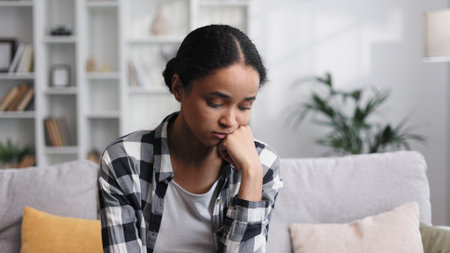 Attractive African American girl sitting in living room, restingの写真素材