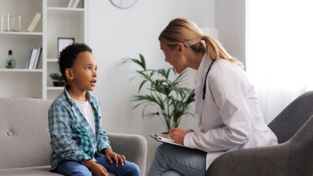 Happy female doctor giving high five to cute little African American boy patient at hospital consultation. A smiling pediatrician will cheer up a small child at the clinic. Healthcare concept.の写真素材