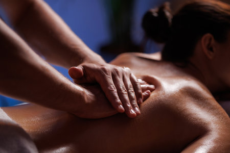Close-up hands of professional masseuse working, massaging womans back in spa salon, therapeutic massage for muscle relaxation. Healing, beauty, health, lifestyle, peace, relief, professional skills.の写真素材