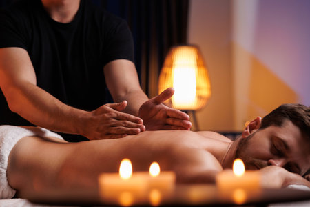 The hands of the male masseur are actively rubbing the visitors back, a therapeutic massage for tired muscles. Point massage in the spa center. Body therapy for a healthy lifestyle.の写真素材
