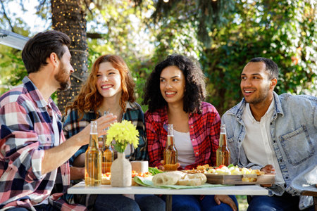 A group of friends are relaxing in nature. Boys and girls of different nationalities and races have fun talking, telling stories, and having fun outside the city.の写真素材