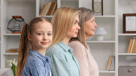 Cute little girl posing indoors with young mother and senior grandmother, side profile view, closeup portrait. Lifespan, next generation, offspring and heredity. For Mothers Day.の写真素材