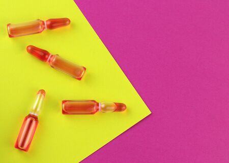 Ampoule and syringe with red liquid on colorful background. Flu vaccination. Catch-up immunization.の写真素材