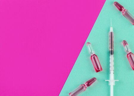 Ampoule and syringe with red liquid on colorful background. Flu vaccination. Catch-up immunization.の写真素材