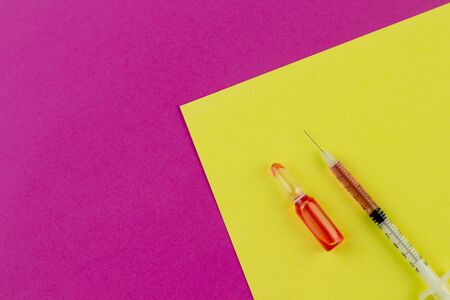 Ampoule and syringe with red liquid on colorful background. Flu vaccination. Catch-up immunization.の写真素材