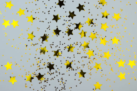 Golden stars on grey background. Plastic shiny stars as bright background. Christmas or New Year...