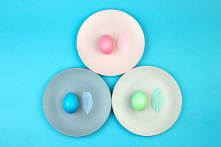 Easter multi-colored eggs and feathers on blue background. Happy Easter greeting card.の写真素材