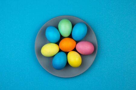 Easter multi-colored eggs on plate on blue background. Happy Easter greeting card.の写真素材