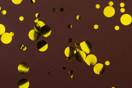 Yellow gold metallic confetti dots on brown background.Holiday celebration concept. Festive...
