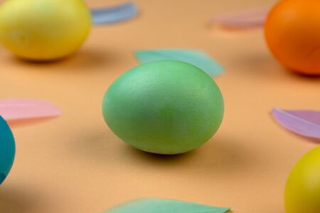 Easter composition of multicolored colorful easter eggs and feathers on pastel background. Green egg closeup. Happy Easter holidays. Flat lay. Top view.の写真素材