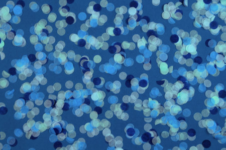 Festive multicolored confetti scattered on blue background. Flat lay style. Holiday concept. Pastel...