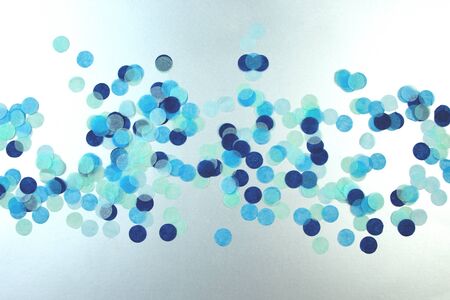 Festive multicolored confetti scattered on blue background. Flat lay style. Holiday concept. Pastel polka dots texture.の写真素材