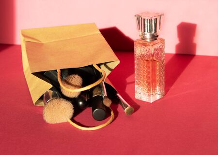 Woman flat lay makeup background with set of decorative cosmetics with dark shadows. Cream, lipstick, perfume, mascara and brush. Top view on pink background, copy space.の写真素材