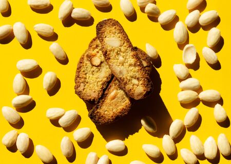 Creative pattern almond cookies and almond on yellow background with shadow. Nut Minimal concept. Mockup, almond close up as package design element.の写真素材