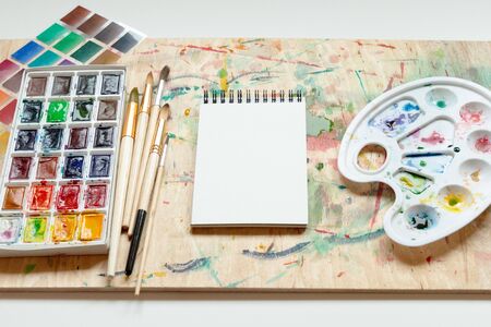 Set of watercolor paints, art brushes, palette and empty sketchbook. Art creativity concept.の写真素材
