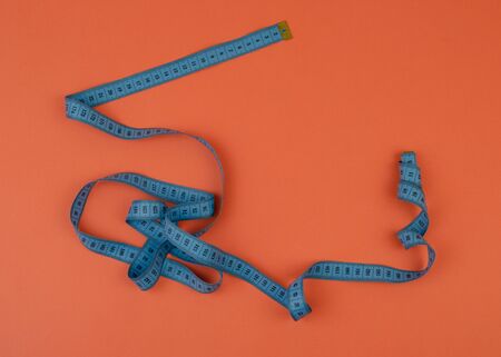 Blue tailor measuring tape on orange background with copy space.の写真素材