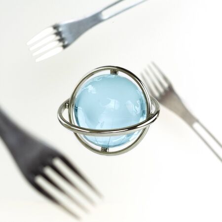 Satellite forks fly around a glass transparent ball. Blue planet Zero Gravity. Environmental and food concept.の写真素材