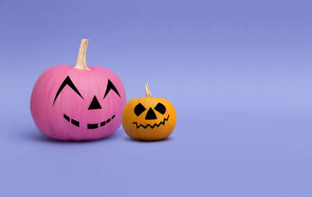 Two colorful pumpkins with smile on a purple background. Minimalist halloween concept.の写真素材