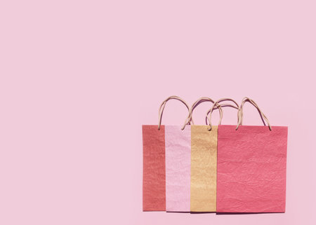 Colorful textured paper shopping bags on pink background. Minimal fashion shopping online concept....