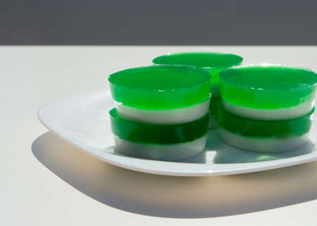 Two-layer jelly made from pandanus leaves and coconut milk. Traditional Thai street food. Lao Wun. Modern minimalist still life. Natural green dye.の写真素材