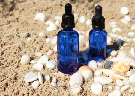 Natural cosmetic skincare bottle container from blue glass with a pipette for feminine hygiene stands on stone with sand, beige background. Skincare essence for beautiful healthy skin.の写真素材