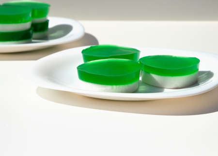 Two-layer jelly made from pandanus leaves and coconut milk. Traditional Thai street food. Lao Wun. Modern minimalist still life. Natural green dye.の写真素材