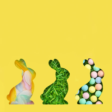 A silhouette of a rabbit is cut out of paper. Background of green grass. Happy Easter greeting card in trendy colors. Yellow and gray are the colors of 2021. Vertical shotの写真素材