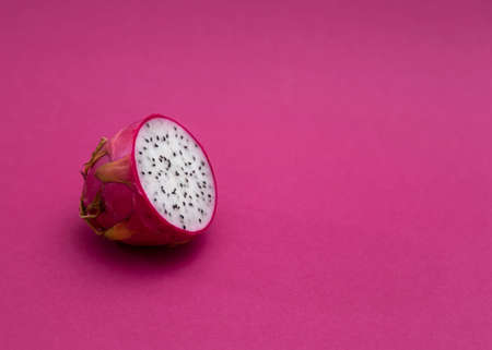 Half of a dragon fruit with white flesh. The pink pitaya fruit is low in calories, rich in essential vitamins and minerals, and contains dietary fiber.の写真素材