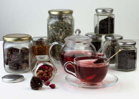 Homemade herbal tea. A remedy that boosts immunity and relieves stress. Glass teapot and tea with a healthy drink. Transparent jars with dried herbs and berries.の写真素材
