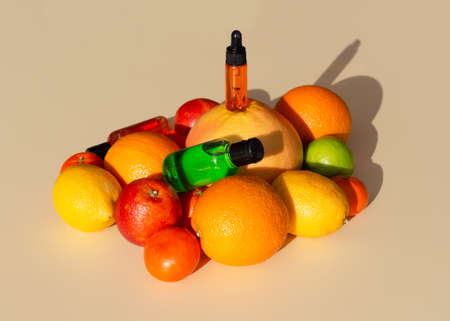 Vitamin C serum in a cosmetic bottle with a dropper on a citrus set. Orange, grapefruit, lime, tangerine, lemon. Organic SPA cosmetics with orange oil. Hard shadow.の写真素材